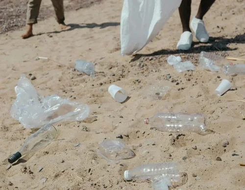 Discarded plastic bottles, cups, and other litter scattered on the beach.