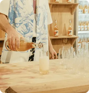 A person pouring a drink into a plain stemless bettercup on a wooden counter at the Canva’s company year-end party.
